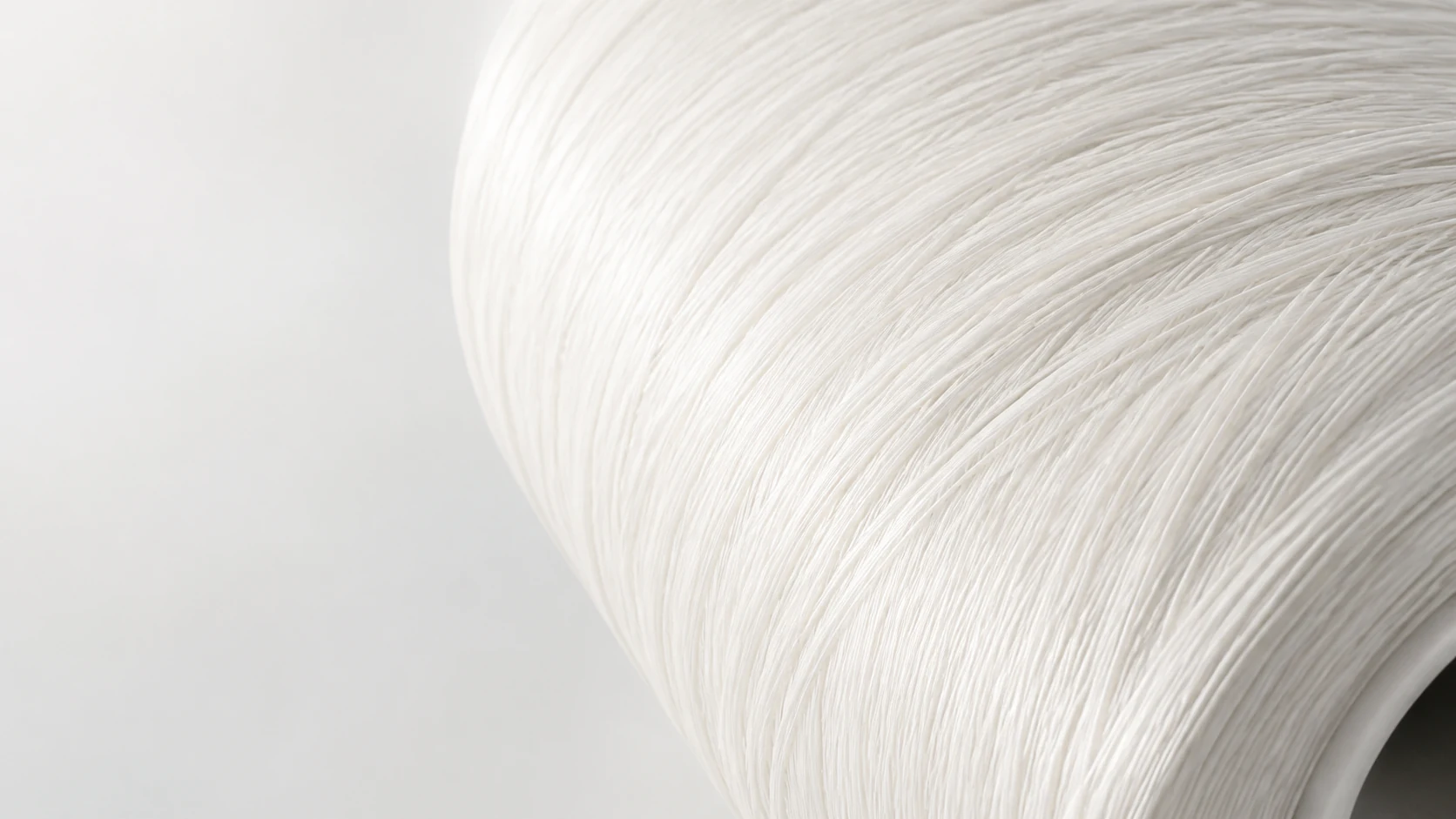 A luminous macro view of thousands of warm-white technical fibers wrapped around a cylindrical form.